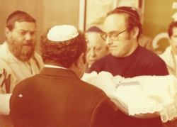 ברית צפריר הר שושנים במשטרה 1979. משמאל: המוהל שקול, אמיר מן (אחיה של נורית הרשושנים)  מחזיק את התינוק (באדיבות שילה הרשושנים, תמוז תשפ"ד 2024)