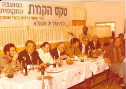תשמ"א 1981. הקמת המועצה המקומית אלקנה. בשולחן הכבוד: יוסף בורג, ניסן סלומינסקי, בני קצובר, המושל הצבאי של יו"ש בנימין בן אליעזר (פואד). צילם: עקיבא איזנברג [באדיבות רחל ועקיבא איזנברג, תשפ"ה 2025]
