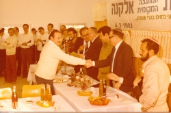 תשמ"א 1981. טקס הקמת המועצה המקומית אלקנה. חלוקת תעודה לניסן סלומינסקי. צילם: עקיבא איזנברג [באדיבות רחל ועקיבא איזנברג, תשפ"ה 2025]